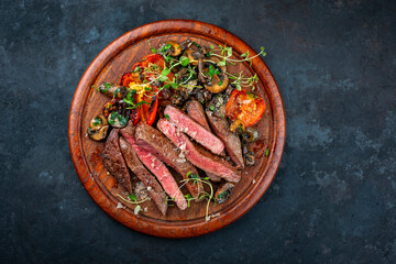 Traditional barbecue grass-fed dry aged roast beef steak tagliata with grilled mushrooms and vegetables cut on wooden board served as top view on a wooden board