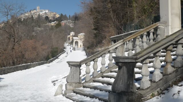 Sacred way of the Sacro Monte di Varese or Santa Maria del Monte with in the background the medieval village, UNESCO site. Panorama from the 7th chapel, views of the 8th and 9th chapels in winter