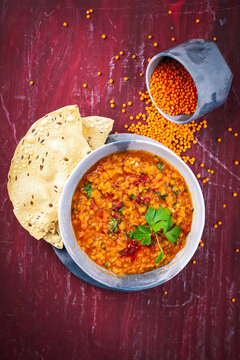Indian dal fry red lentils with chili papadam servied as top view in a design bowl