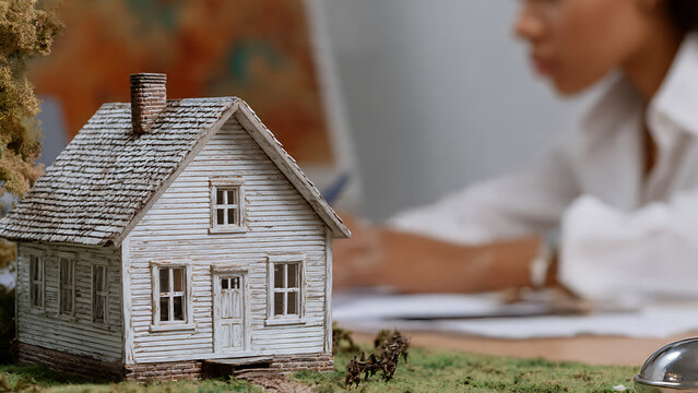 Banquier signant un contrat de pr&ecirc;t immobilier devant une maison miniature, id&eacute;al pour article ou blog sur l'immobilier