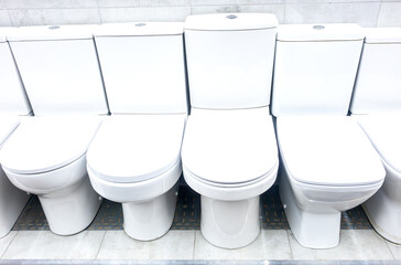 Assortment of ceramic toilet bowls are located in a plumbing store