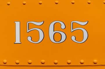 Number 1565 on orange panel with rivets