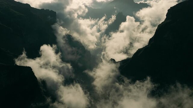 Aerial drone footage captured near Pico do Arieiro on Madeira Island during golden-hour conditions. The drone flies forward above a dramatic mountain valley along the PR1 Vereda do Areeiro route
