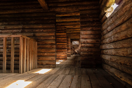 Ancient wooden fort interior with repeating doorways, log construction, and sunlight on the floor, representing medieval architecture and historical defense design.
