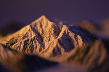 Goldenhour mountain peak with rugged terrain and sunlight shining on rocky surface with blurred foreground