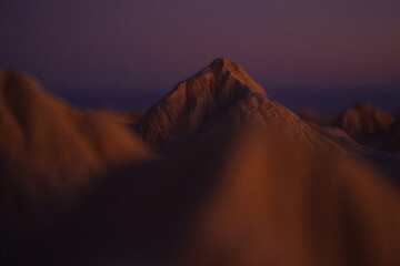 Majestic mountain peak bathed in the warm golden light of sunrise or sunset with dramatic clouds swirling around its base creating an atmospheric and breathtaking landscape vista