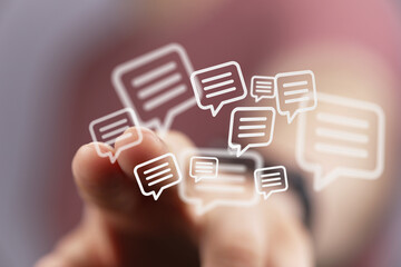 Close up of a hand interacting with a digital communication concept, featuring floating chat bubble icons, representing social media networking