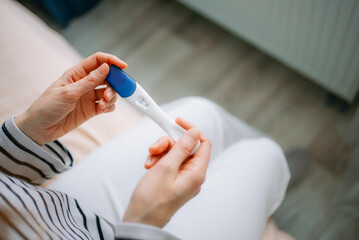 Woman holding pregnancy test showing a positive result, confirming pregnancy and motherhood, anticipating a new baby and family planning decisions, with focus on fertility and future