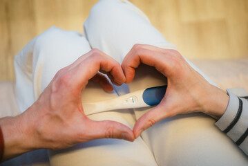 Expecting parents' hands forming a heart shape, lovingly embracing a positive pregnancy test, symbolizing new life, anticipation, and the joy of coming parenthood