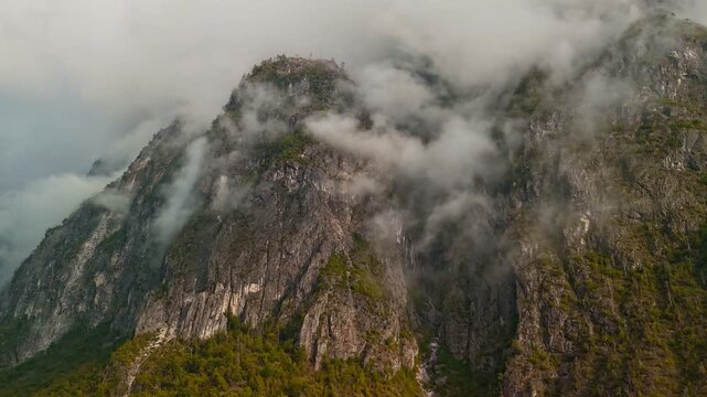 Aerial drone hyperlapse flying forward through fog and clouds between Dolomites mountain peaks, Italy