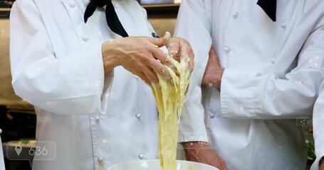 Pulling left chef's hands stretching dough at commercial kitchen counter, with mixing bowl, jackets