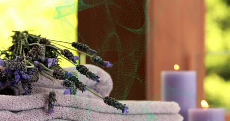 Resting dried lavender bundle on terry towels at spa table near wooden panel, lit purple candles