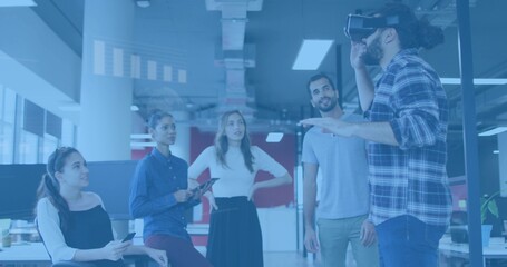 Showing man wearing plaid shirt gesturing in VR headset in open office, tablet visible, copy space