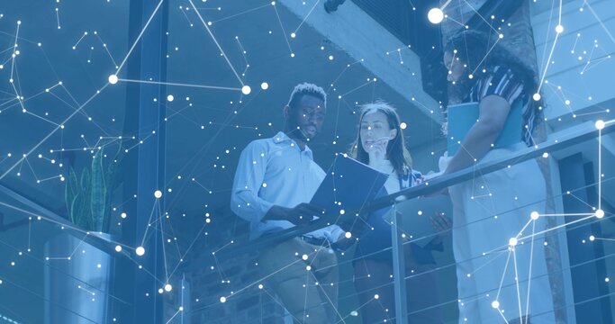 Reviewing documents, team wearing business checking tablet by mezzanine railing, digital overlay - Powered by Adobe