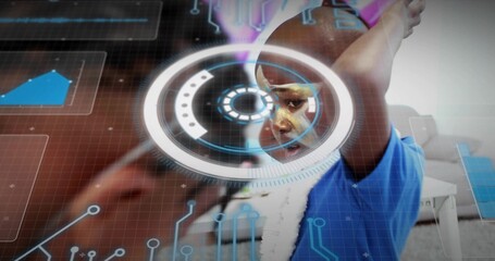 Raising arms, boy in blue tee white scarf aligning face with hologram HUD inside room, forearm