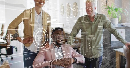 Reviewing seated man in wheelchair wearing pink blazer guiding team through HUD overlays in office