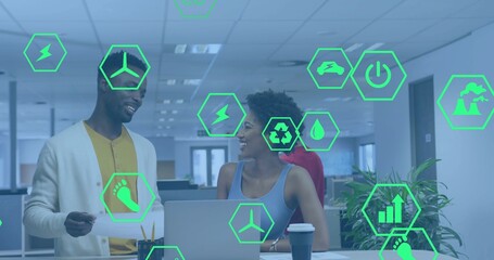 Discussing three colleagues reviewing laptop in open office, showing green hexagon icons overlay