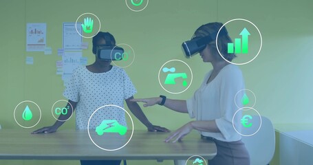 Exploring two female colleagues wearing white blouses, VR headsets viewing AR eco metrics in office