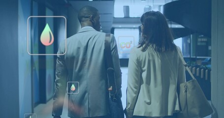 Walking blazer-clad duo carrying shoulder bag, tote and umbrella in blue office hall, showing CO2