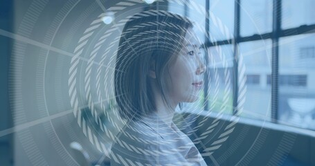 Gazing Asian woman wearing pale blouse, facing right in studio by large window, spiral overlay
