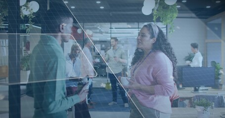 Chatting woman in pink sweater, headband holding white cup in modern office with monitors, lanyard