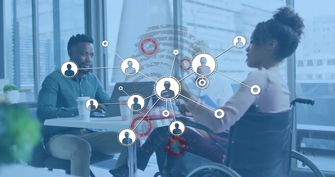 Discussing team reviewing data in office at round table, with laptops, wheelchair, network overlay - Powered by Adobe