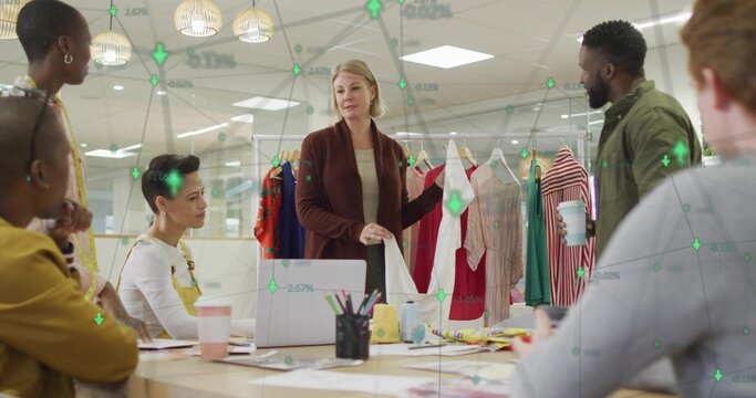 Holding white garment, lead presenter in brown cardigan leading review at office with clothing rack - Powered by Adobe