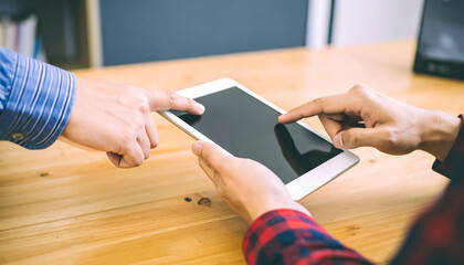Two people discussing and using a tablet together while collaborating on a project
