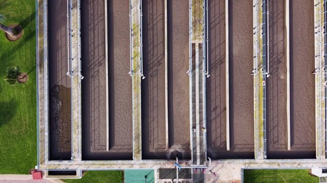 Top-down aerial view of a wastewater treatment plant in Spain, showcasing sedimentation channels, processing basins, and solar-equipped infrastructure in a clean geometric layout