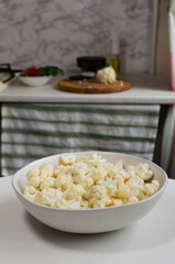 Cauliflower florets in a large bowl on a white table