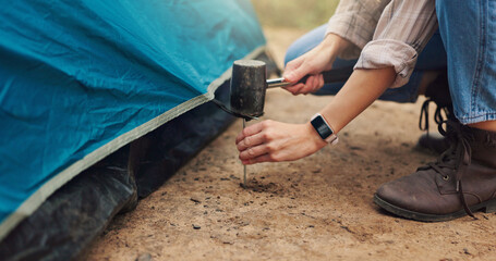 Hands, person and tools for pitching tent for camping adventure, setup preparation and holiday. Woman, hammer and assemble shelter of equipment security, survival skills and vacation safety in nature