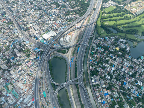 Aerial view of the intricate web of elevated highways and roads cutting through the urban landscape, juxtaposed against the green golf course, Dhaka, Dhaka Division, Bangladesh.