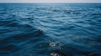 Fototapeta premium Vast expanse of deep blue ocean water with gentle waves under a clear sky