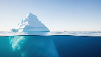 Large iceberg floating in calm ocean water with clear blue sky and turquoise underwater reflection