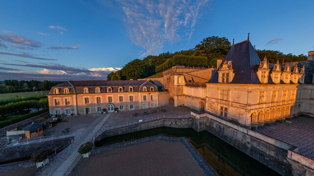 Aerial view of the Chateau de Chaumont, its stone walls aglow under the soft dawn light, contrasting with the deep shadows of the moat, Chaumont-sur-Loire, Centre-Val de Loire, France.