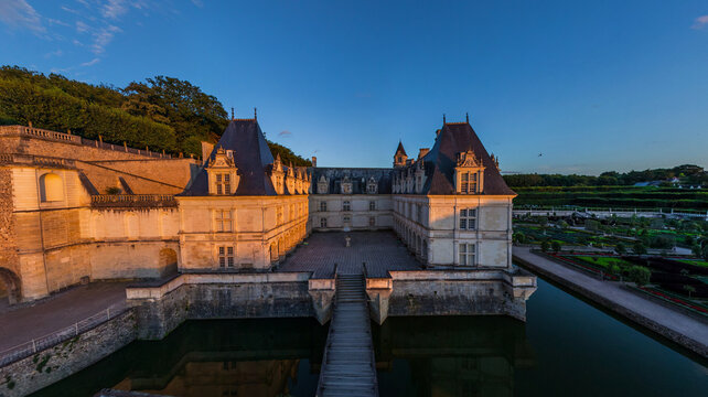 Aerial view of the majestic Chateau de Chaumont, its stone walls reflecting in the surrounding moat under the soft glow of the setting sun, Chaumont-sur-Loire, Centre-Val de Loire, France.