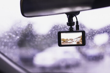Car dashboard camera mounted on a windshield recording video of traffic during heavy rain. Concept of road safety, technology, and insurance evidence.
