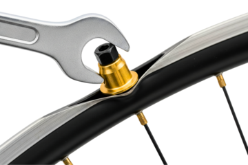 Silver wrench tightening a small gold spoke nipple on a bicycle rim on a transparent background