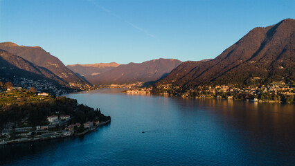 Aerial view of the tranquil lake reflecting the golden light, surrounded by mountains and villas, a picturesque scene of serenity, Como, Lombardy, Italy.