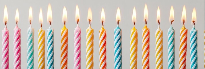 A high-resolution, panoramic studio photograph showcasing a symmetrical row of multiple brightly lit birthday candles against a clean, plain white background.