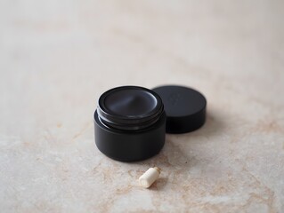 Luxury black cosmetic jar with cream on marble surface