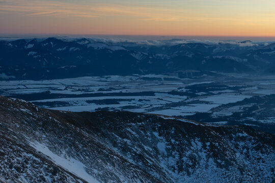 Aerial view of snow-dusted peaks piercing the horizon under a soft sunrise glow, Nizna Bystra, Zilina Region, Slovakia.
