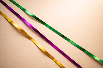 Vibrant Mardi Gras ribbons in purple, green and gold on beige background