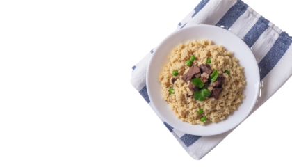 A bowl of food with visible herbs is placed on a blue and white striped cloth napkin in a high angle shot on white and transparent