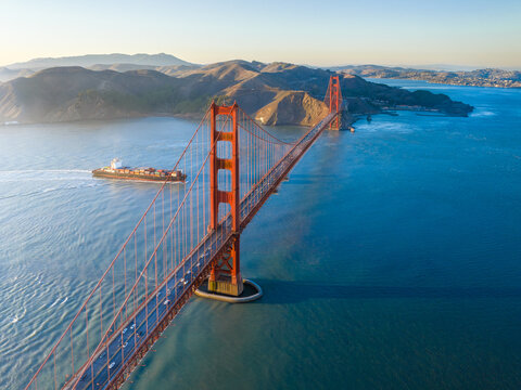 Aerial view of the iconic Golden Gate Bridge stretching across the shimmering bay, a testament to engineering marvel, bathed in the warm glow of the sun, San Francisco, California, United States.