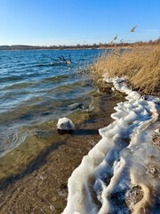 frozen winter beach with waves on the lake