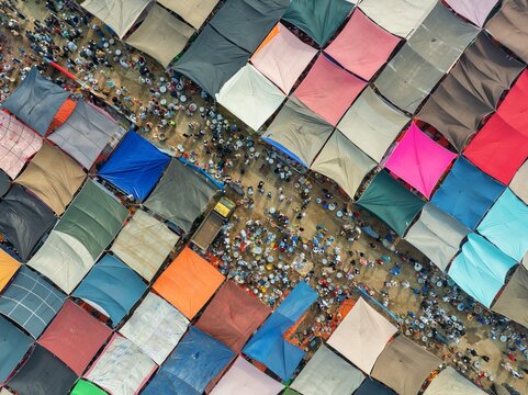 Aerial view of a vibrant tapestry of market stalls, their colorful canopies creating a geometric pattern above a bustling crowd, Tongi, Dhaka Division, Bangladesh.