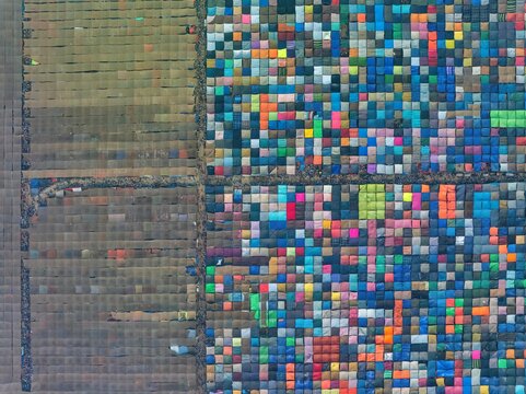 Aerial view of a dense tapestry of colorful structures contrasts sharply with the muted tones of adjacent plots, creating a vibrant mosaic, Tongi, Dhaka Division, Bangladesh.
