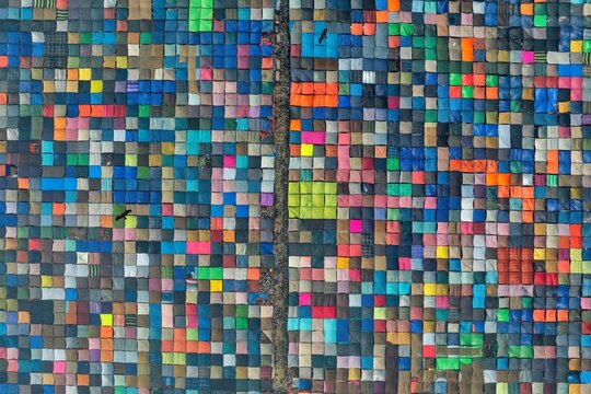 Aerial view of colorful tents clustered tightly together, creating a vibrant mosaic of hues and shades, divided by a narrow pathway, Tongi, Dhaka Division, Bangladesh.