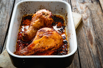 Baked chicken drumsticks in baking dish on wooden table
